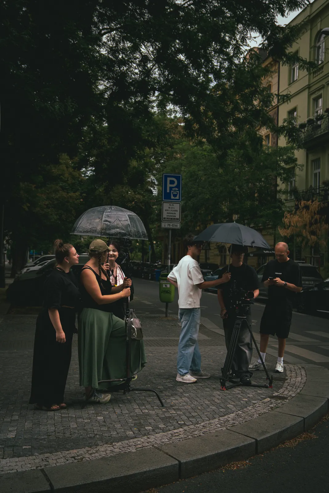 Štáb s deštníky během deštivého natáčecího dne
